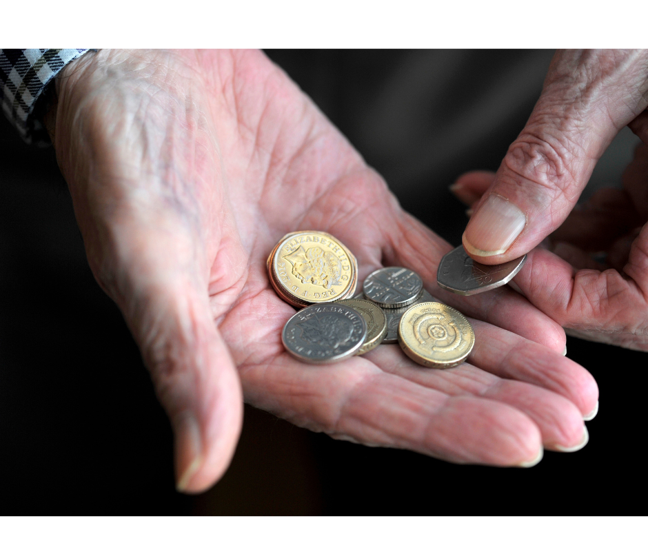 hands belonging to an older person holding coins.