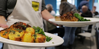 two plates of roast dinner being held by one person, as it about to be served